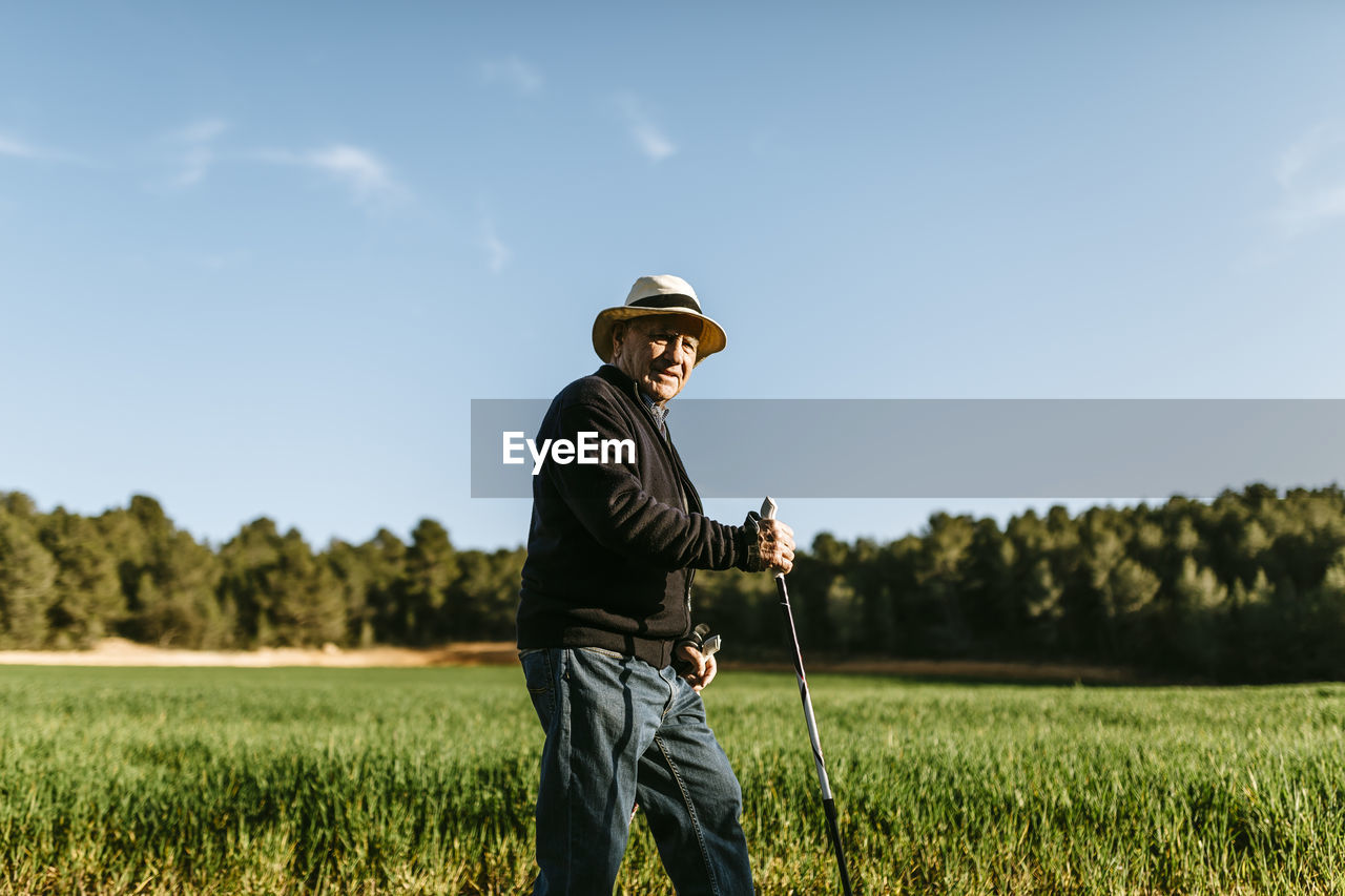 Spain, tarragona, senior man walking with sticks in the field