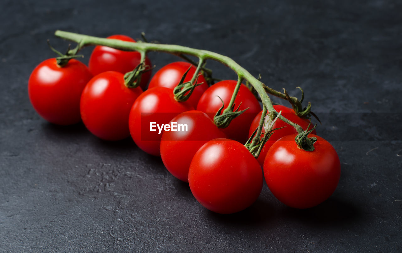Ripe red tomatoes on a green branch. vitamin-rich vegetables. dark background