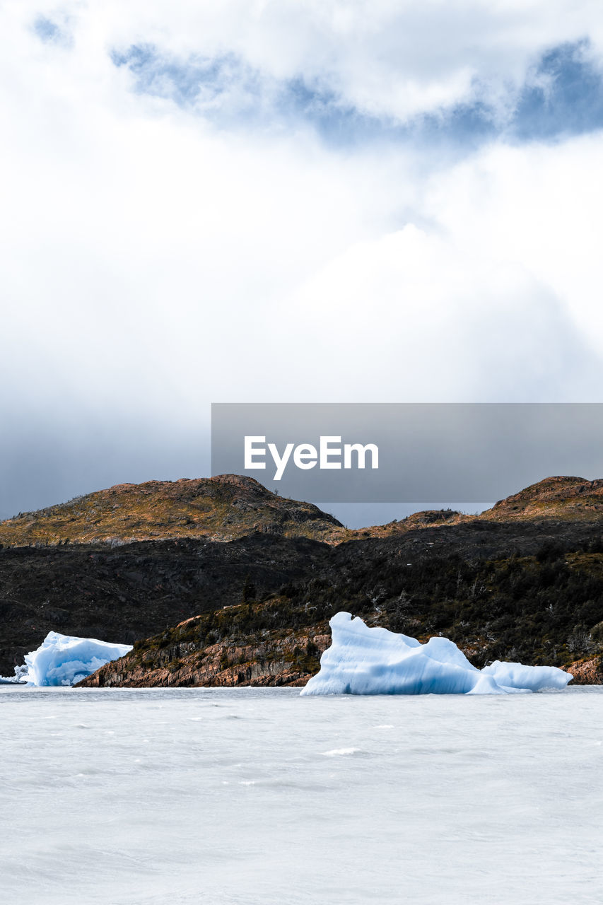 Scenic view of sea by mountain against sky