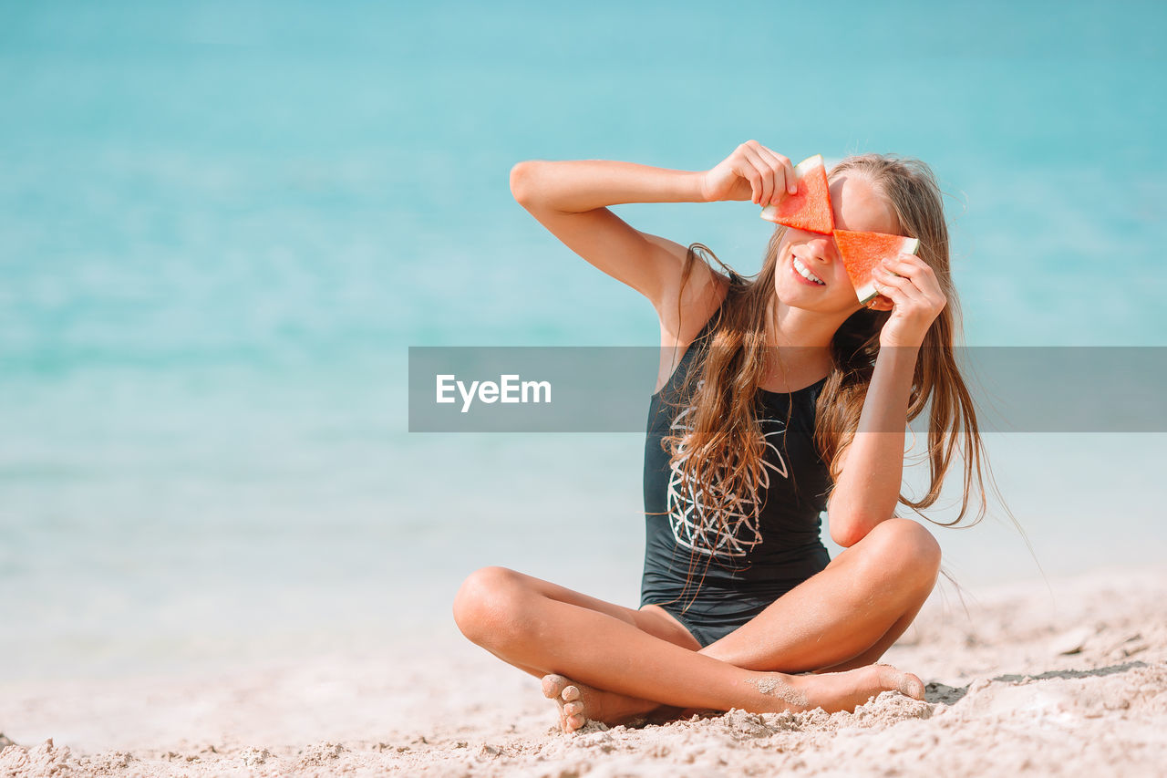 WOMAN SITTING AT BEACH