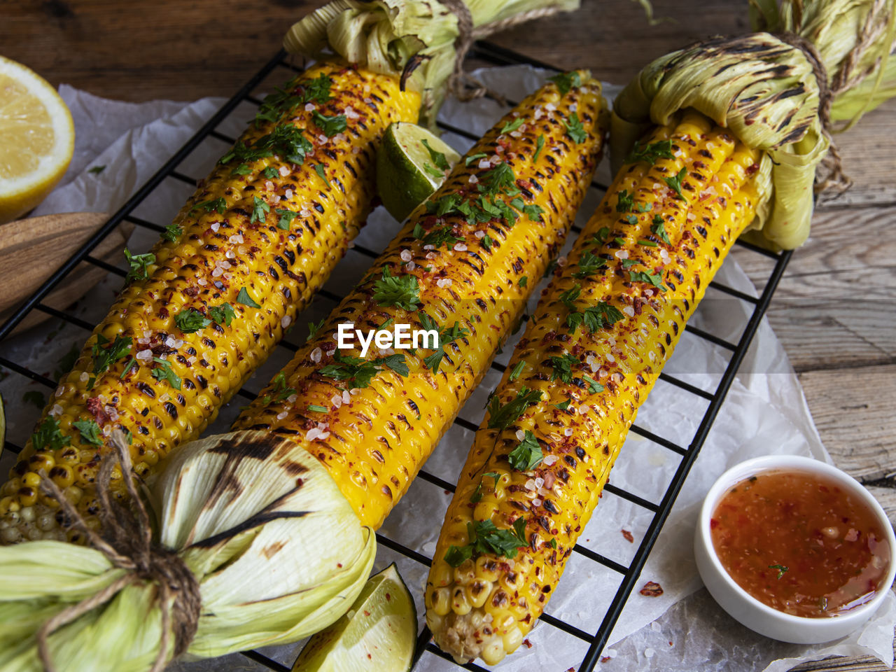 Three heads of yellow corn grilled lemon lime spicy, white orange red sauce, rustic style