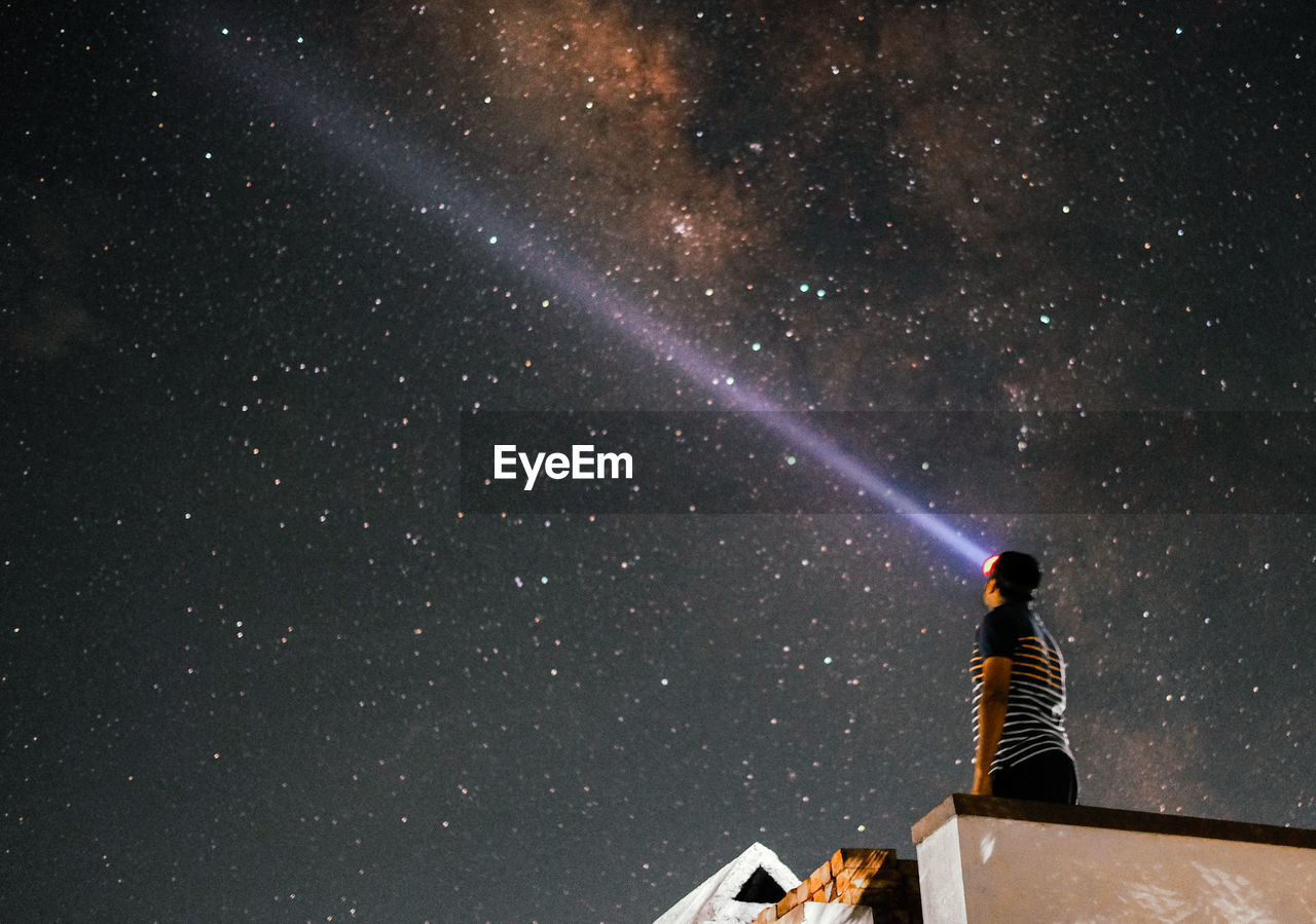 REAR VIEW OF WOMAN STANDING AGAINST STAR FIELD