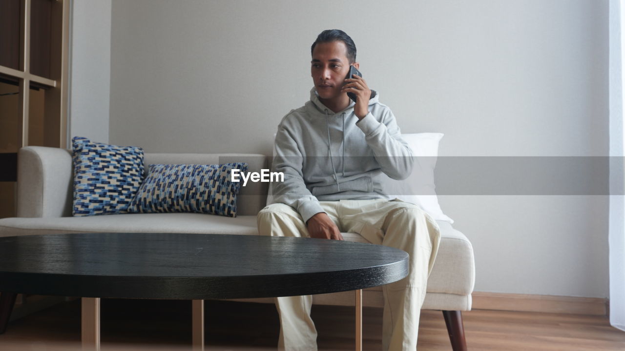 Man on the phone while working in the living room of the house