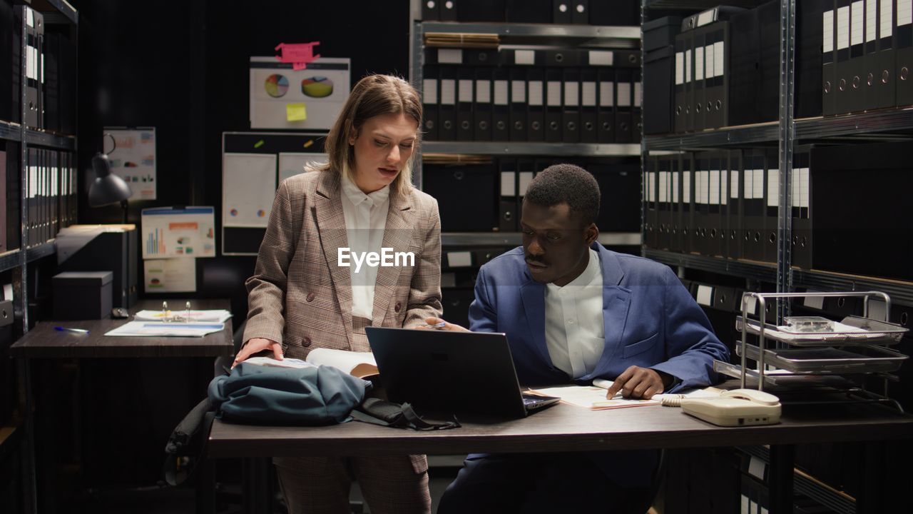 smiling woman using laptop while sitting at cafe