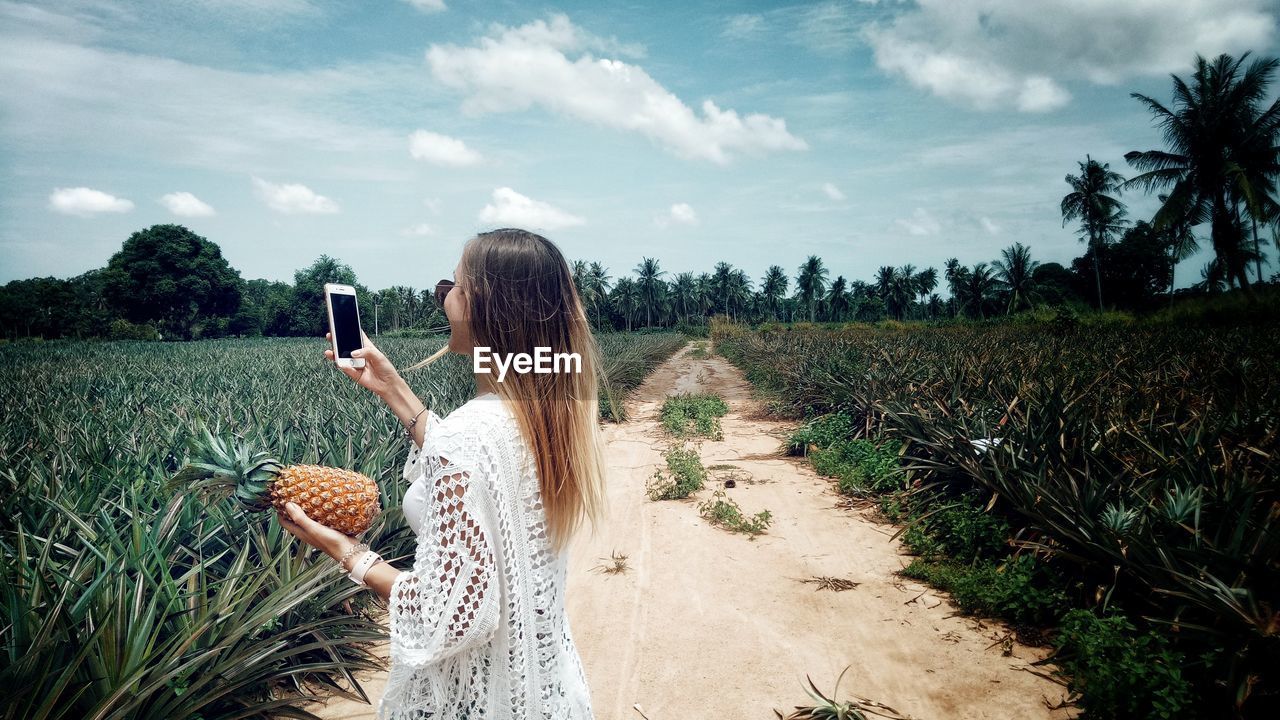 Woman using mobile phone while standing amidst plants