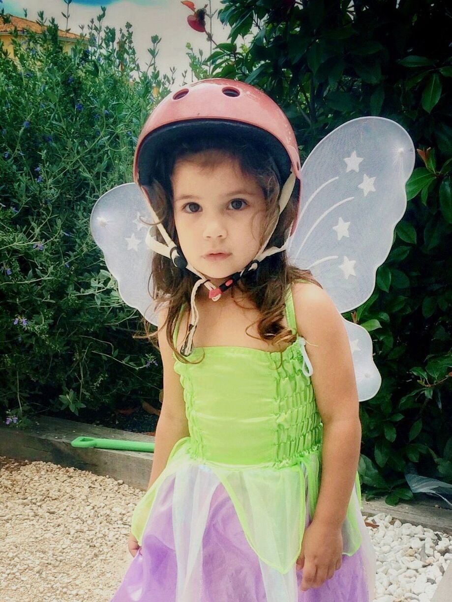 Girl wearing costume wing against plants