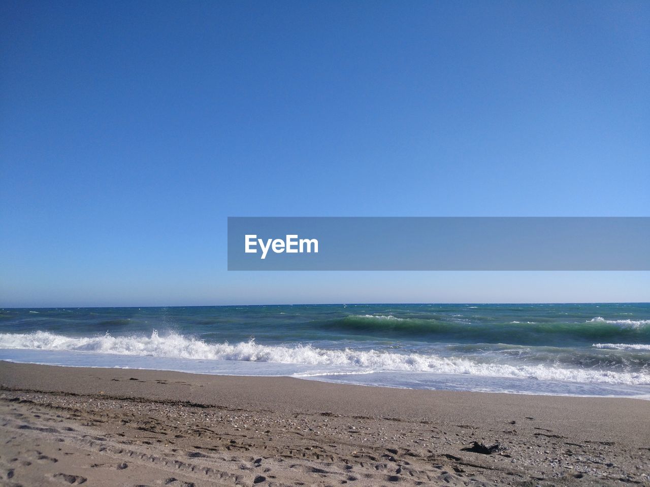 Scenic view of beach against clear blue sky