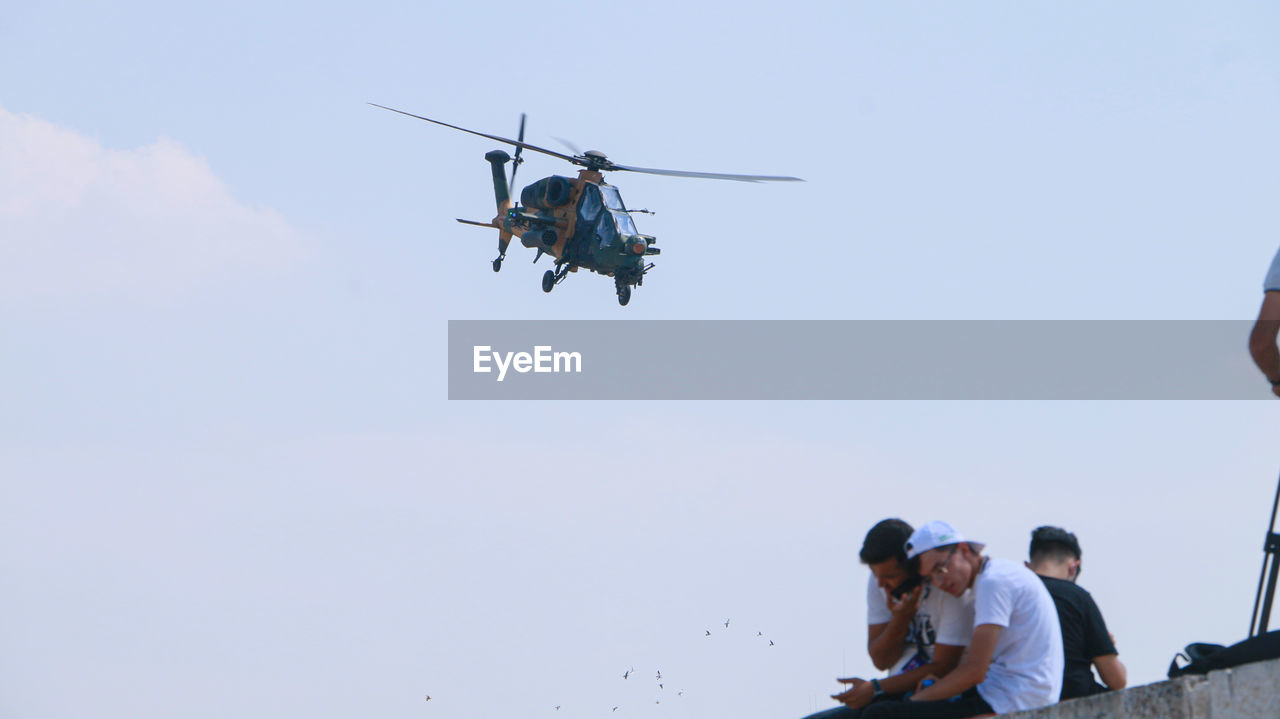 transportation, men, air vehicle, group of people, mode of transportation, adult, sky, helicopter, flying, nature, aviation, air force, aircraft, vehicle, day, mid-air, airplane, togetherness, small group of people, outdoors, cooperation, communication, person, motion, occupation, low angle view, teamwork, young adult