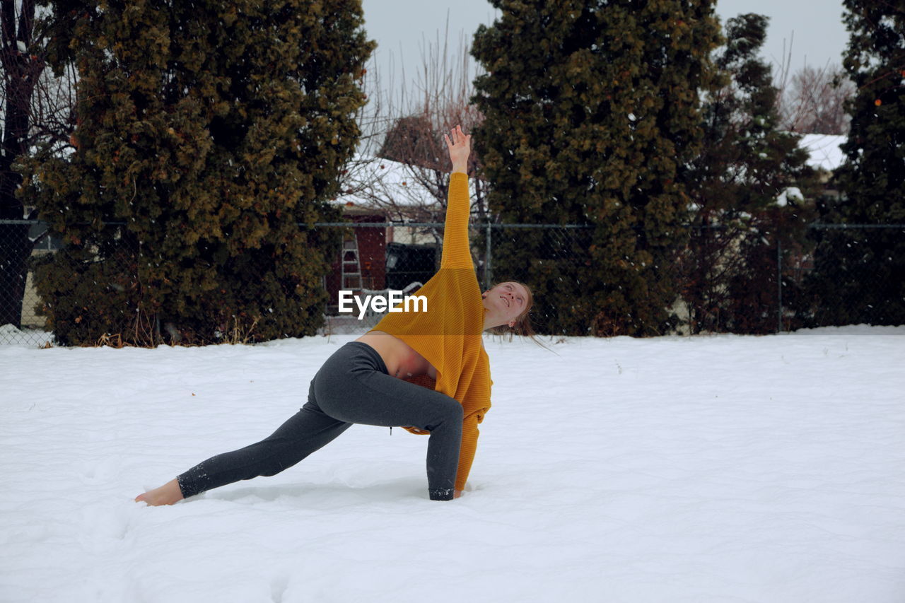 Young woman exercising on snow covered field