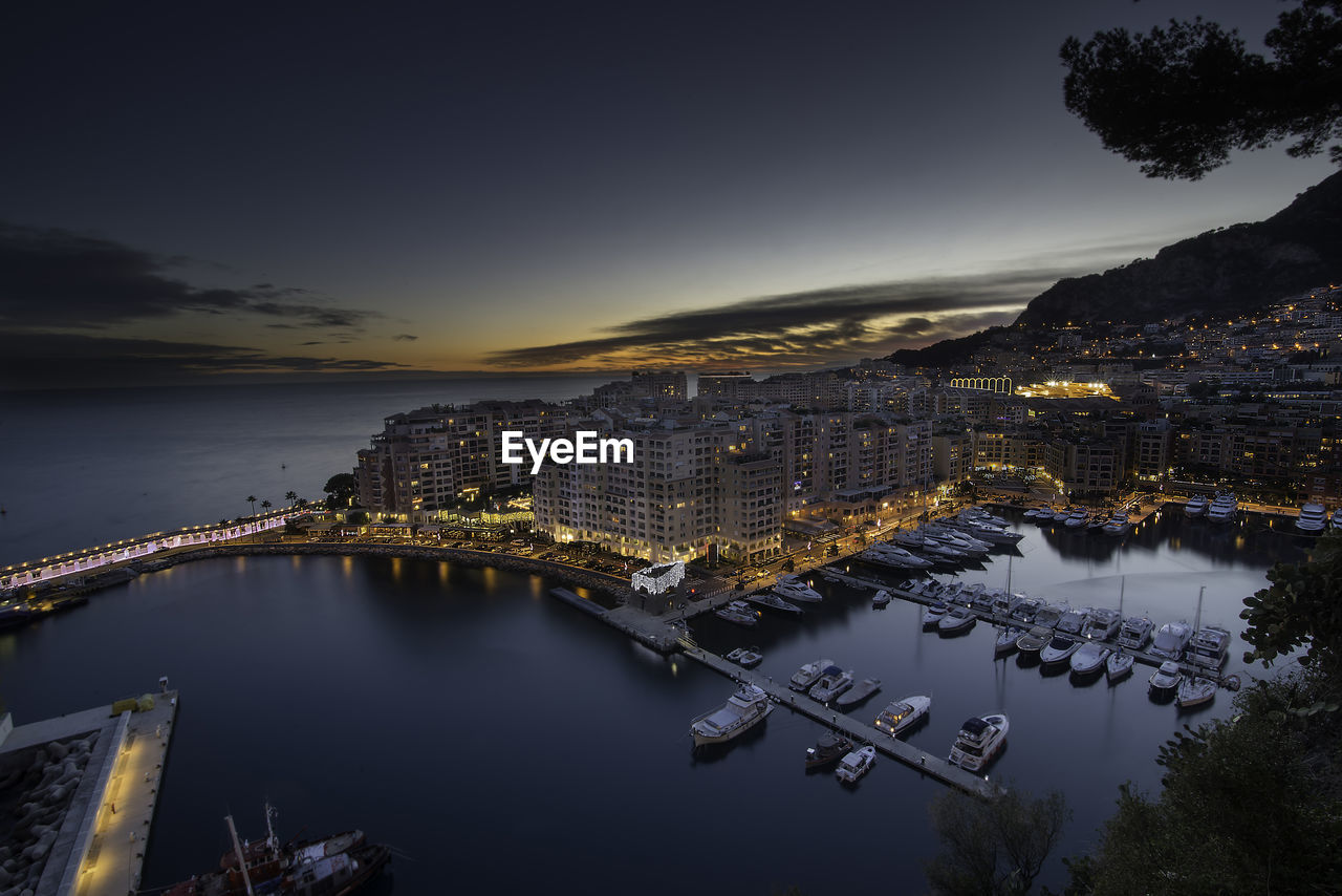 High angle view of illuminated buildings by river against sky