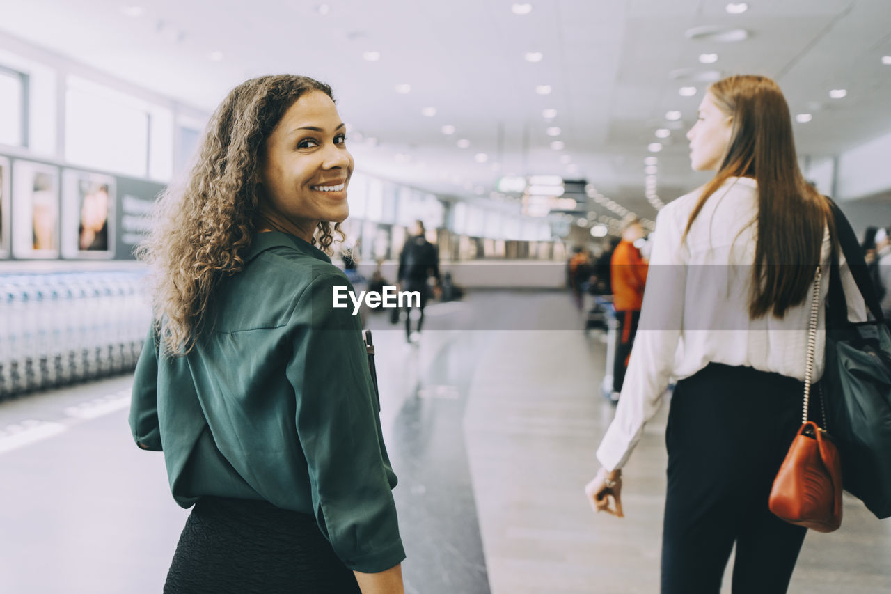 Portrait of smiling businesswoman walking with female colleague at airport