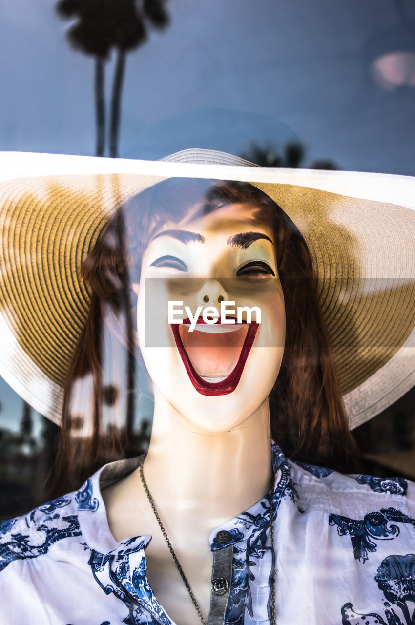 Close-up of mannequin at retail display seen through glass