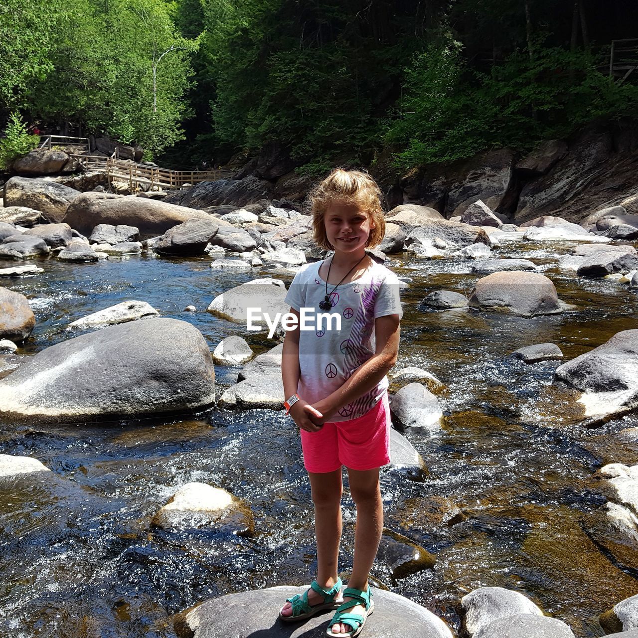 Full length portrait of girl standing on rock at river 