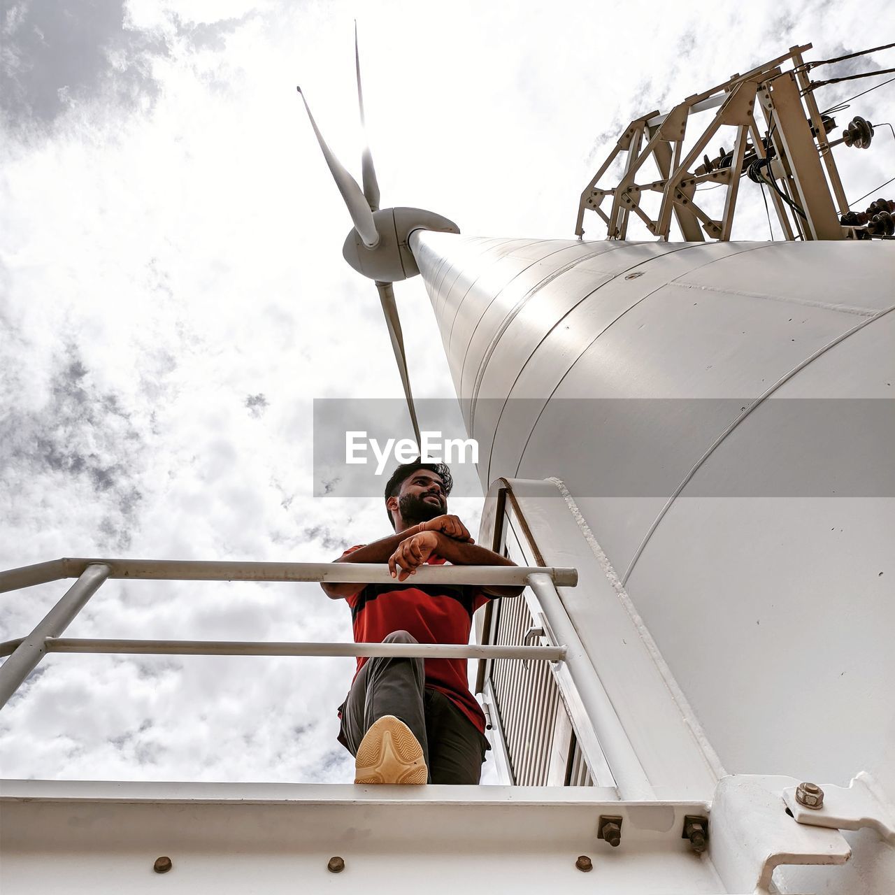 Low angle view of man standing on wind turbine