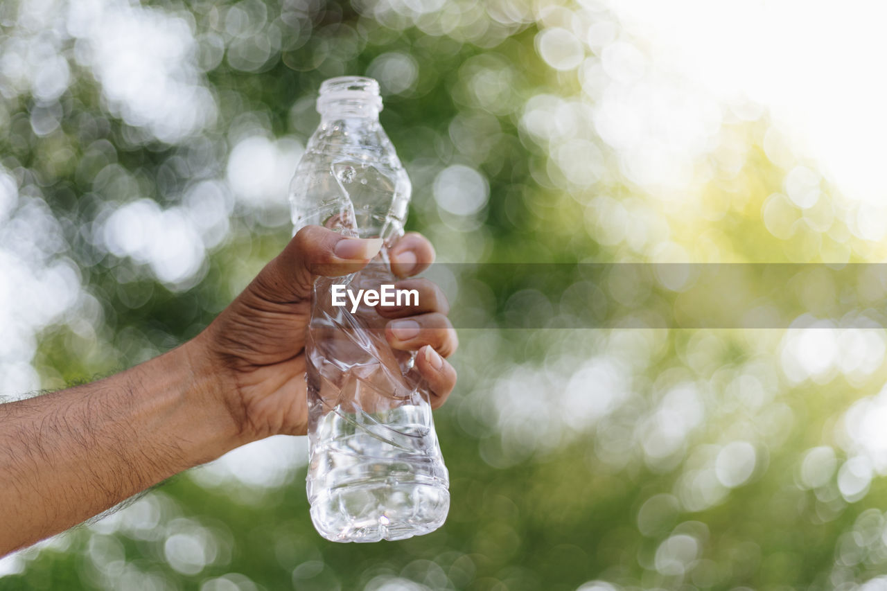 CLOSE-UP OF PERSON HAND HOLDING BOTTLE DURING MONSOON