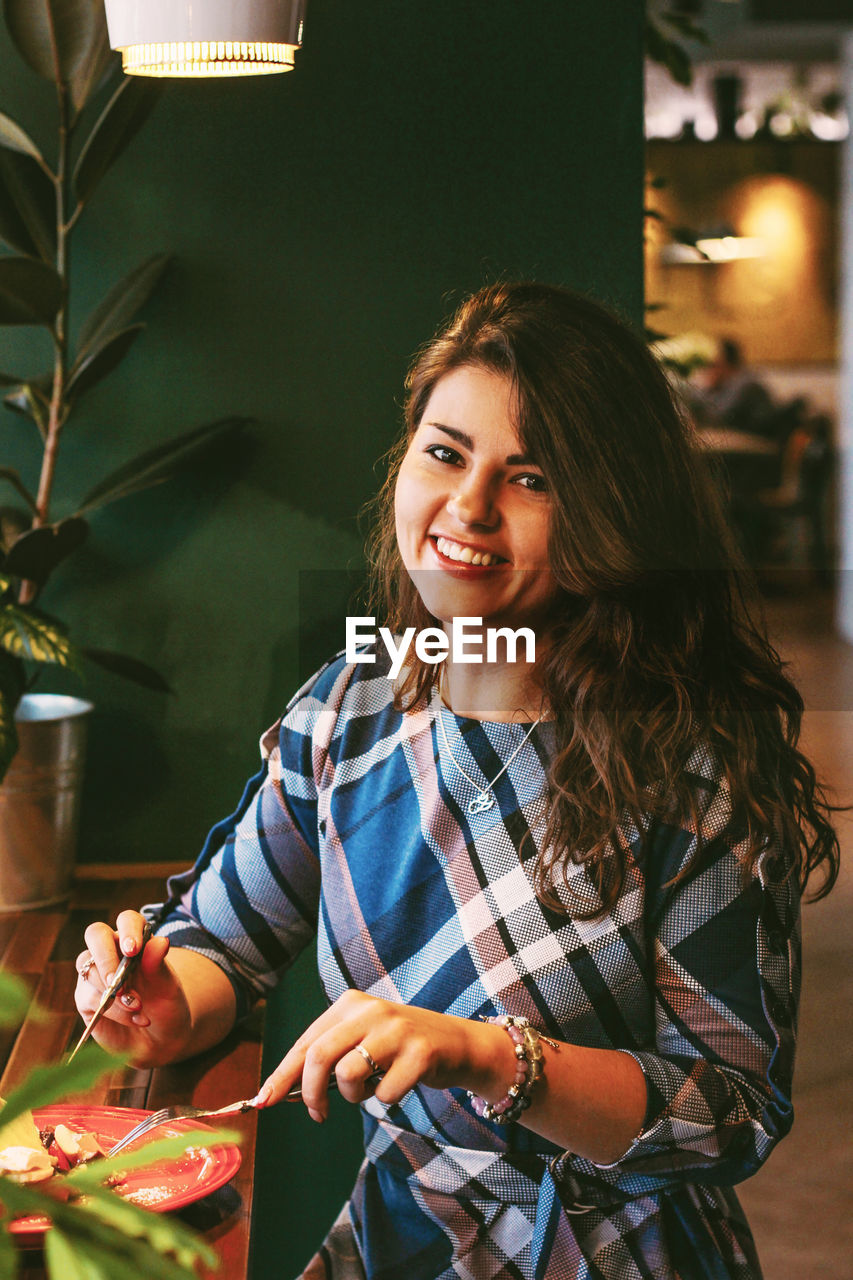 Portrait of a smiling young woman holding food at restaurant