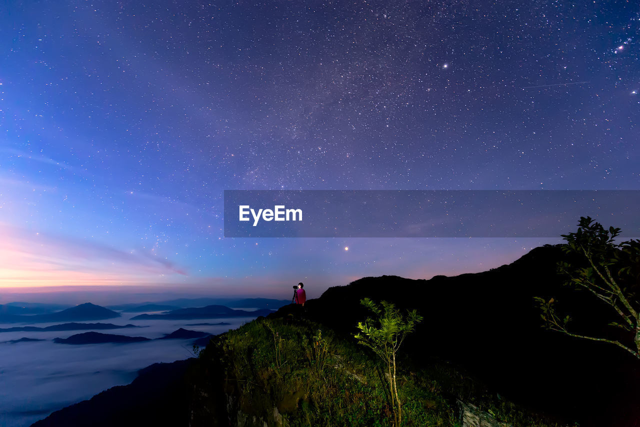 Woman on mountain against sky at night