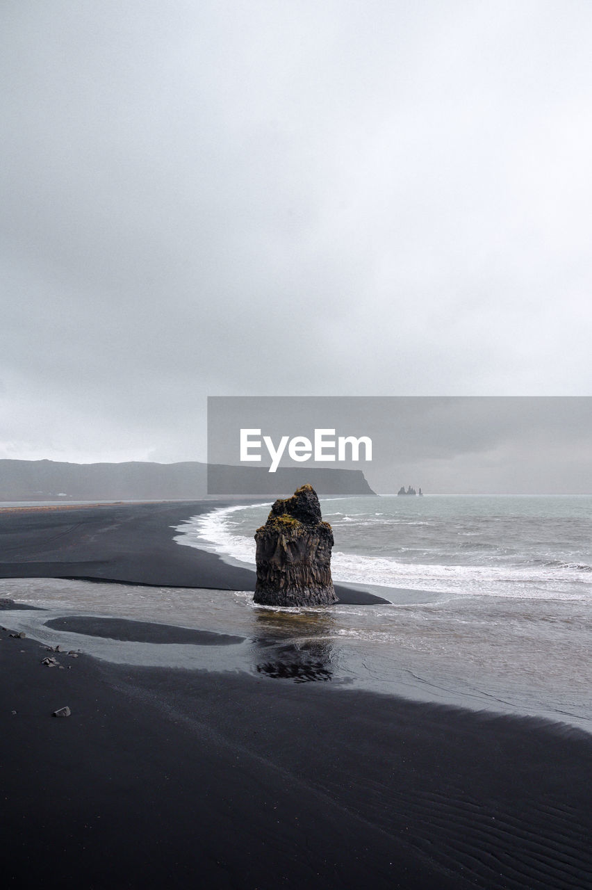 Scenic view of rocks on beach against sky