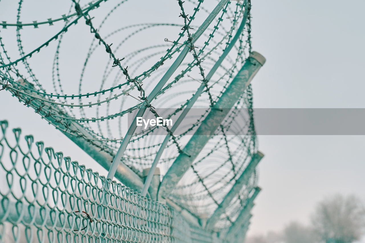 CLOSE-UP OF METAL FENCE AGAINST SKY