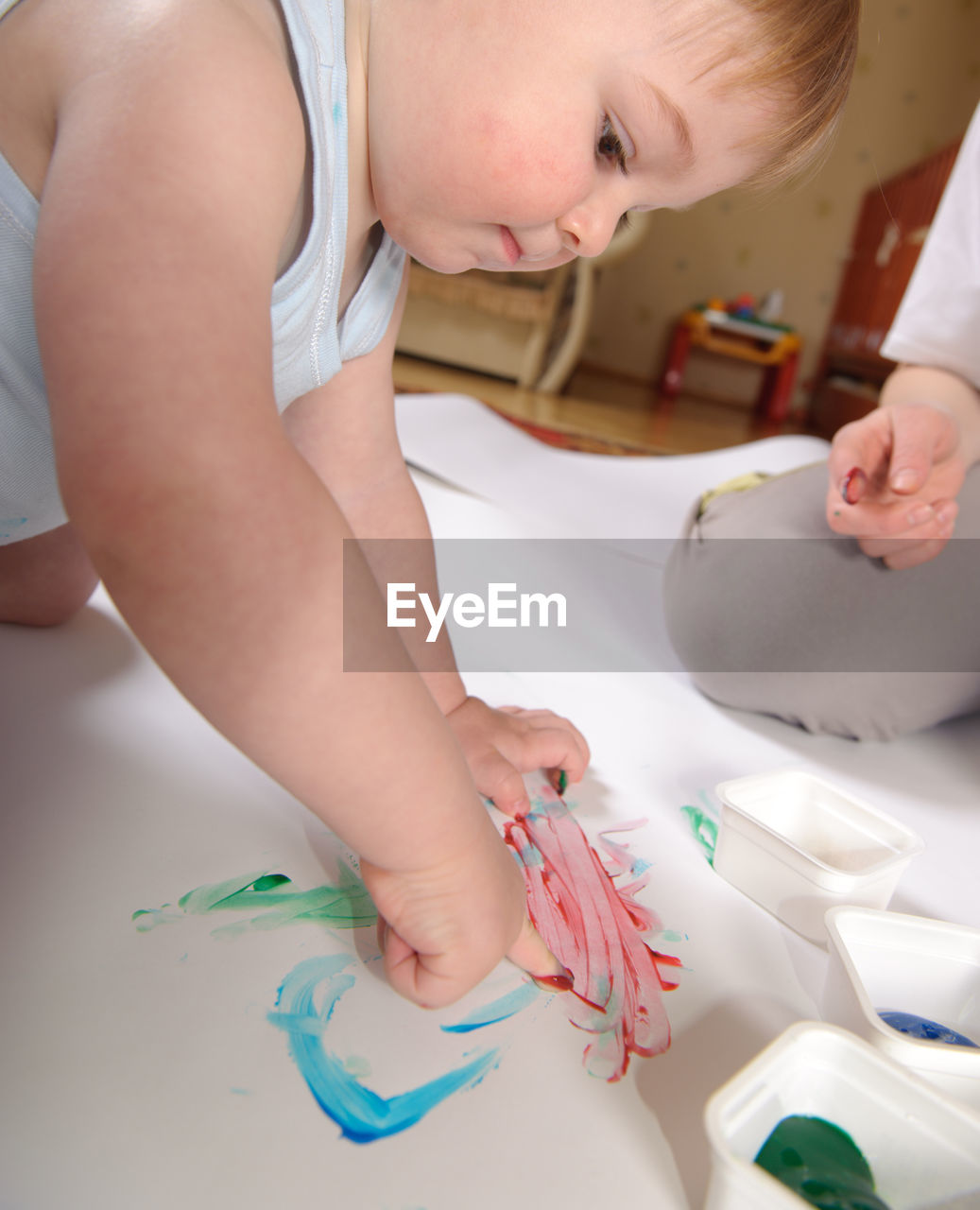 Cute baby boy painting with sister on paper