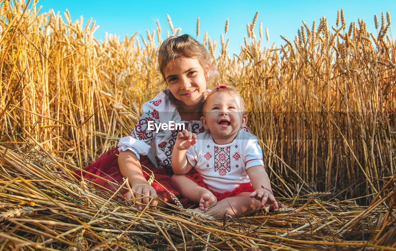 Girl sitting with sister in field