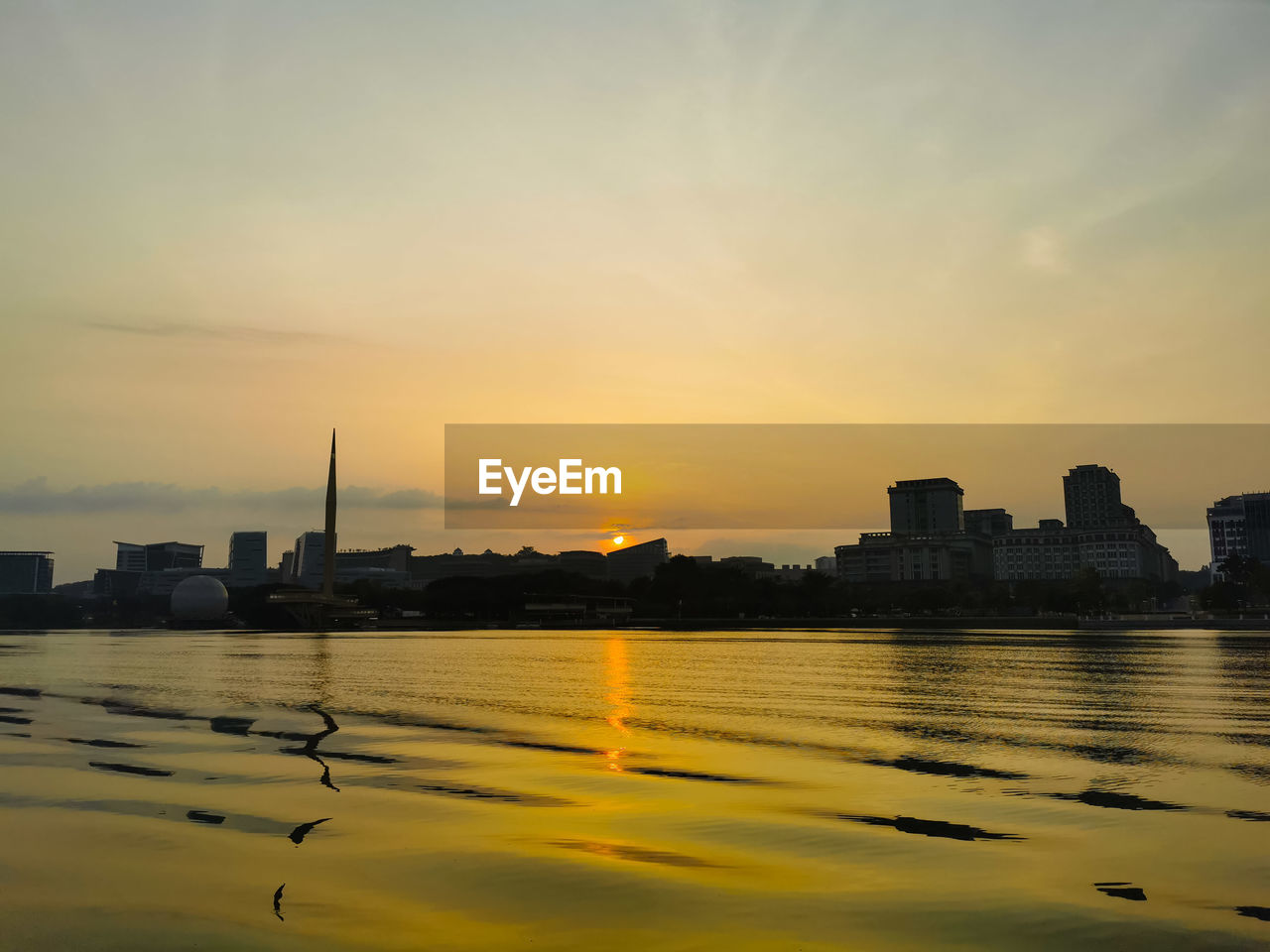 RIVER BY SILHOUETTE BUILDINGS AGAINST SKY DURING SUNSET