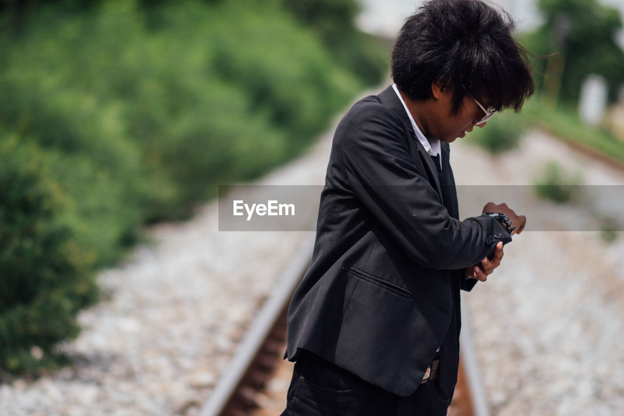 Businessman checking time on railroad track