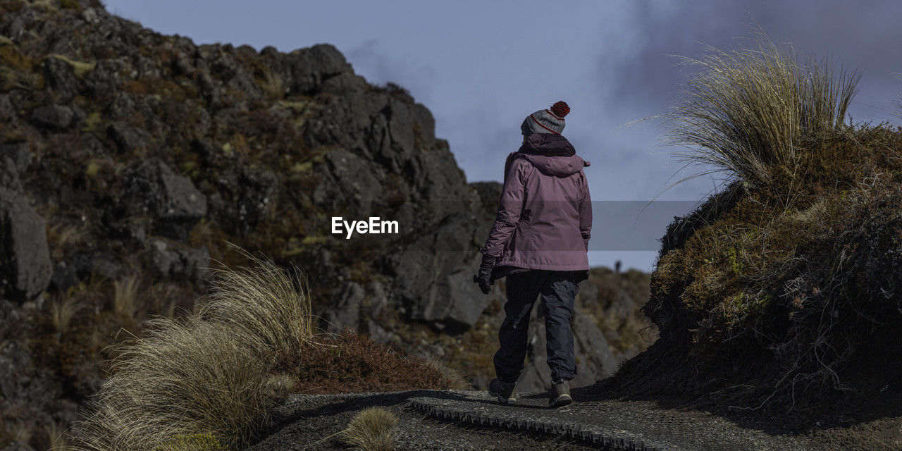 Rear view of a person walking on a pathway in  rugged terrain