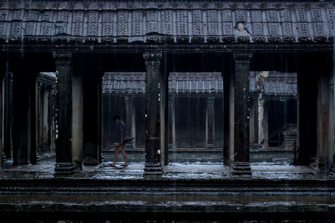 Side view of man walking at angkor wat temple during rains