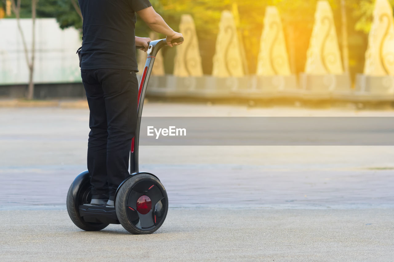 Low section of man riding segway on road