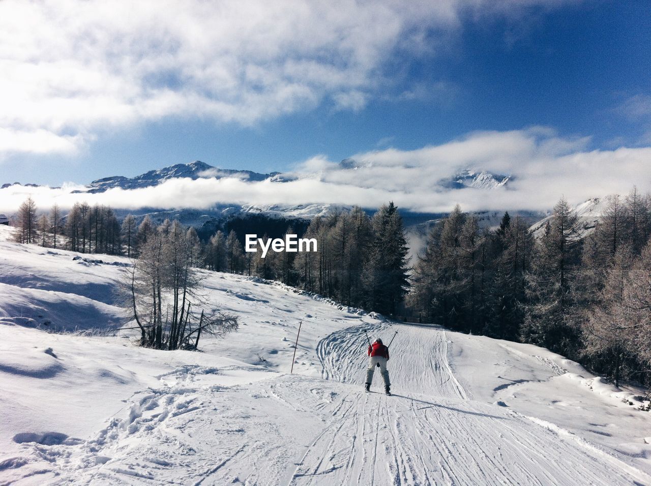 Rear view of person skiing on snowcapped mountain against sky