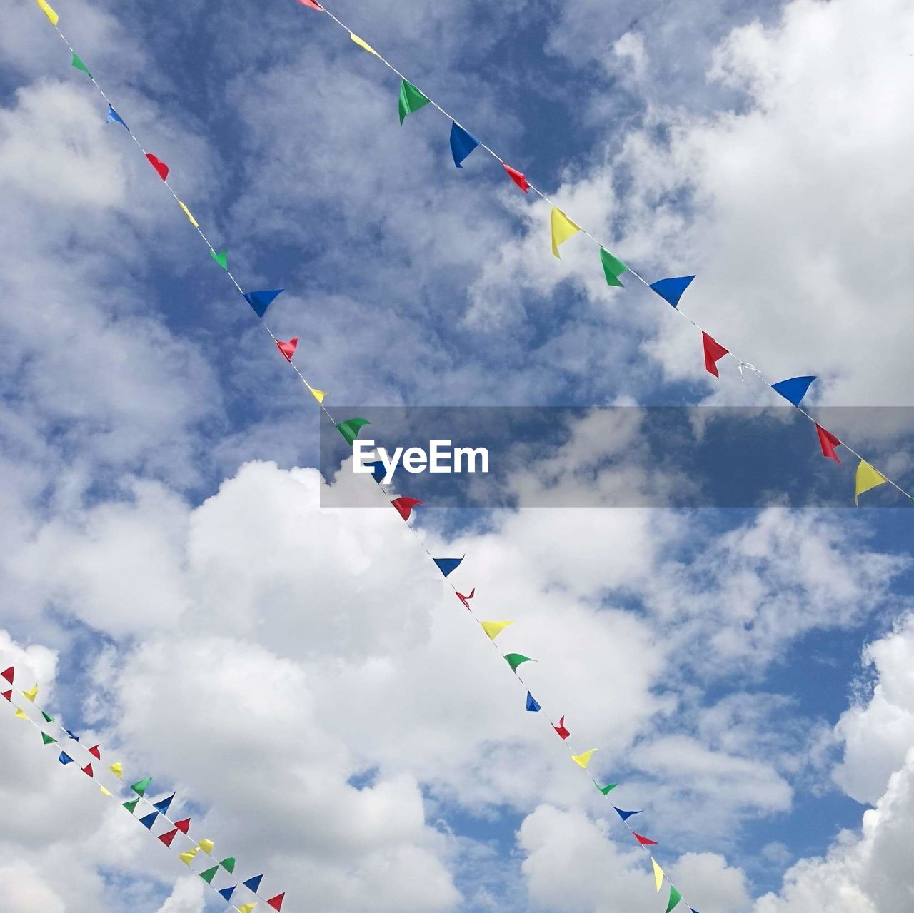 Low angle view of colorful buntings hanging against cloudy sky