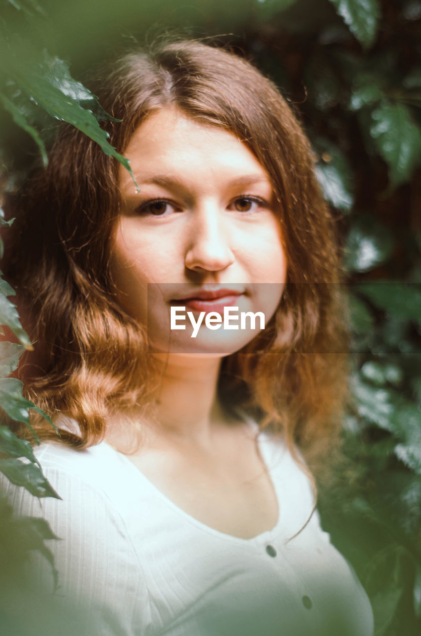 Portrait of beautiful teenager standing by plants outdoors