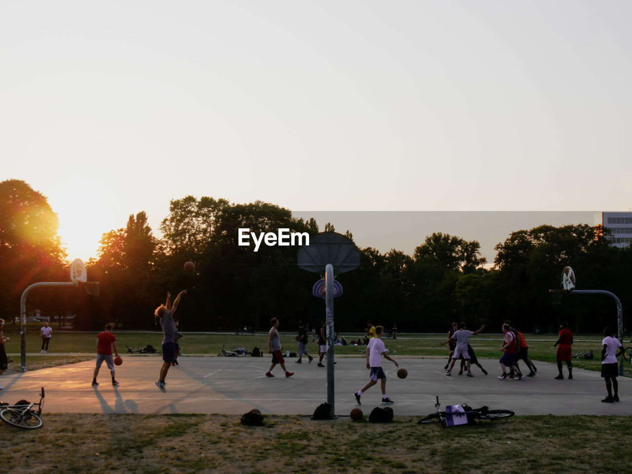 People playing basketball against sky during sunset