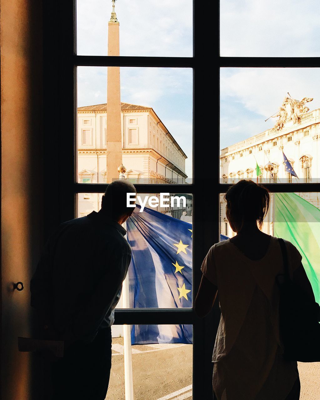 Friends looking through window in city at home