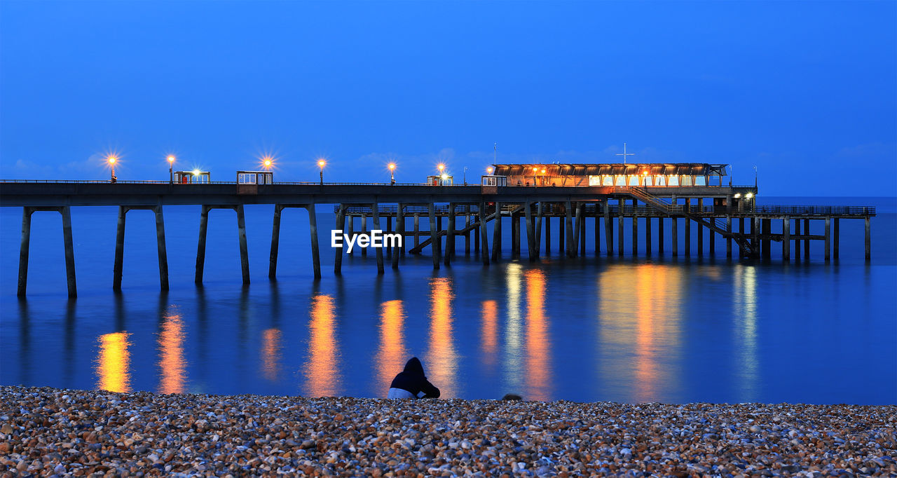 Pier over sea against clear sky at night