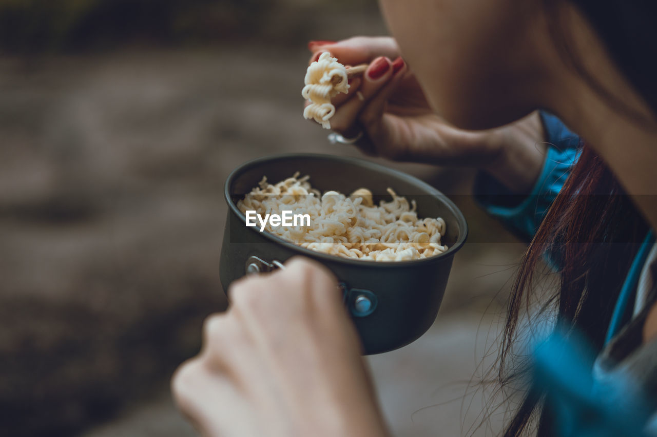 Close-up of woman having noodles outdoors