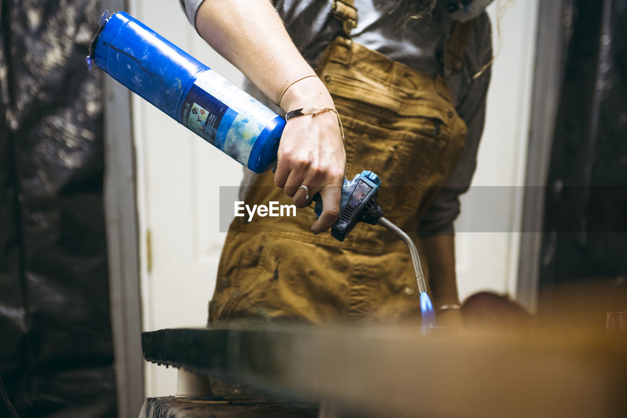 Female resin artist using blowtorch to finish artwork