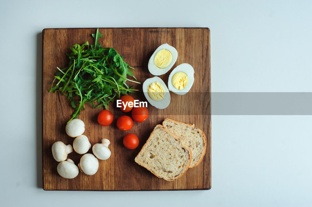 DIRECTLY ABOVE SHOT OF FRUITS AND VEGETABLES ON CUTTING BOARD IN KITCHEN