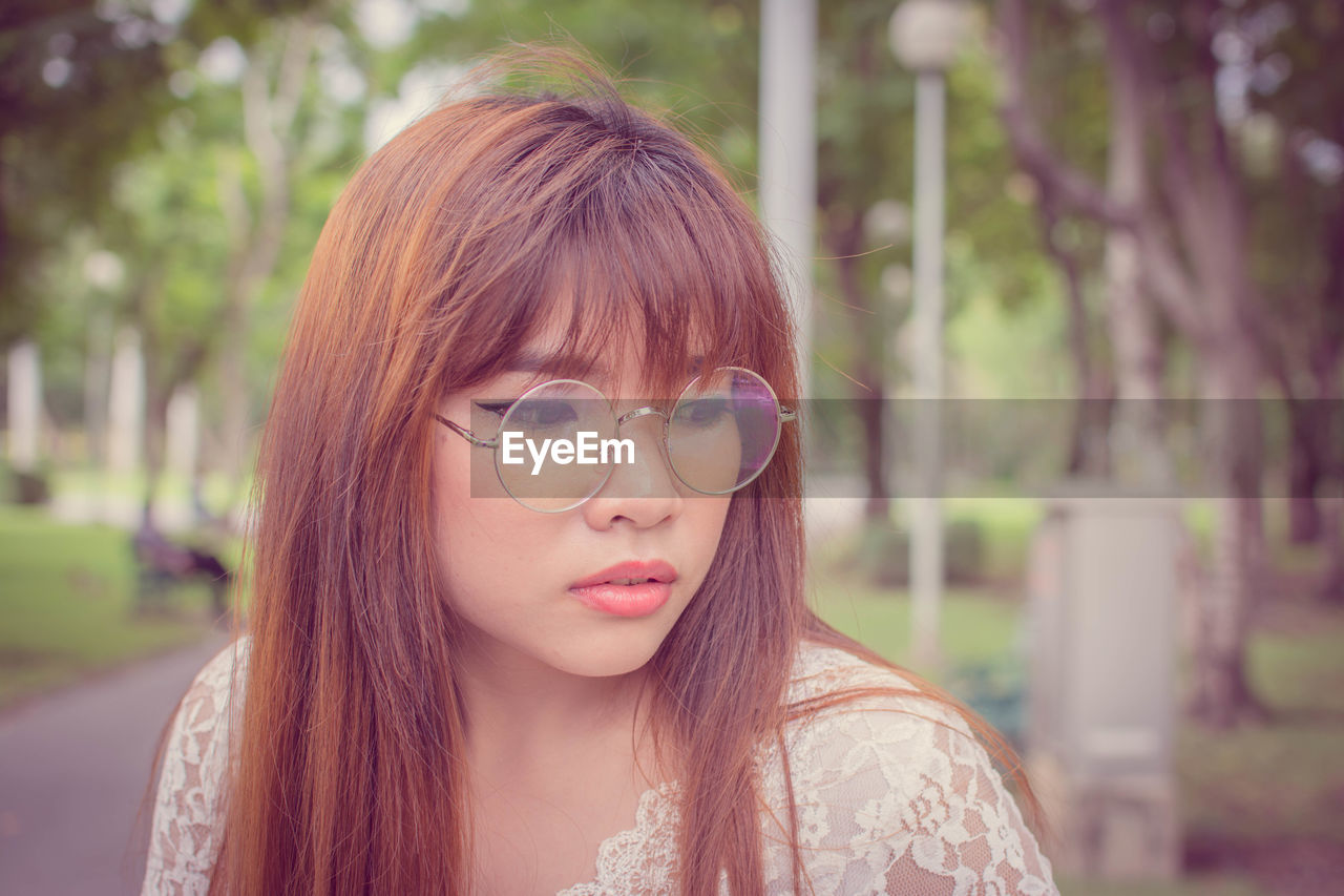 Thoughtful young woman wearing sunglasses in park