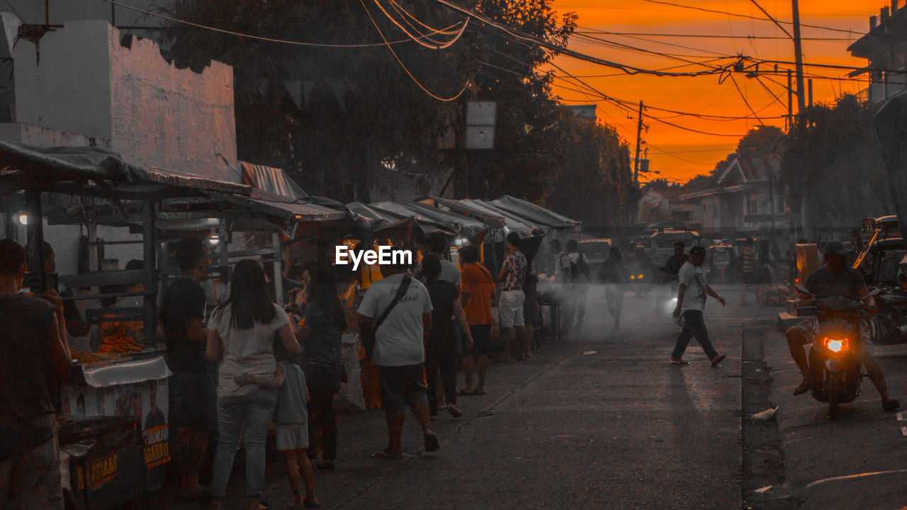 PEOPLE WALKING ON ILLUMINATED STREET MARKET IN CITY