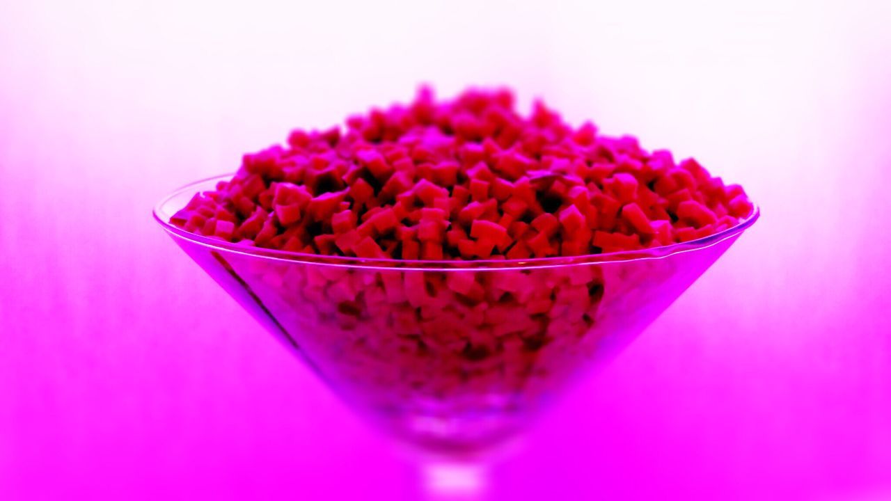 CLOSE-UP OF PURPLE FLOWERS IN BOWL AGAINST PINK BACKGROUND