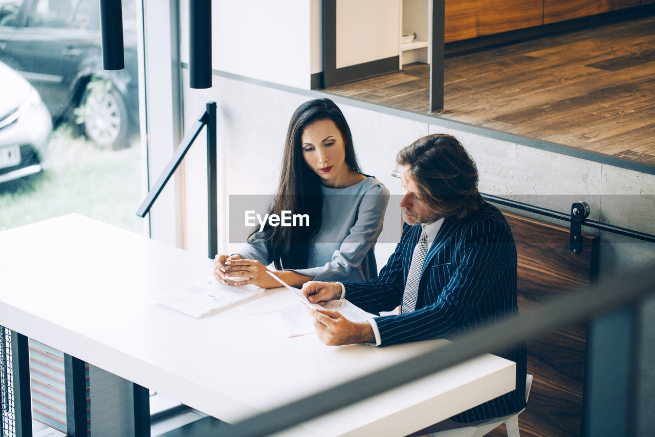 Businessman discussing with colleague at desk in office