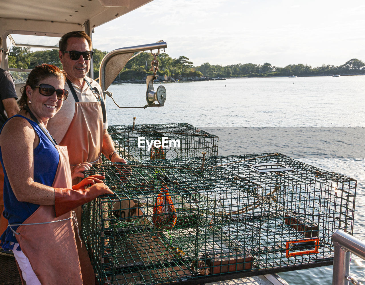 A man and a women are on a lobster boat tour ready to push off two lobster traps back in to water.