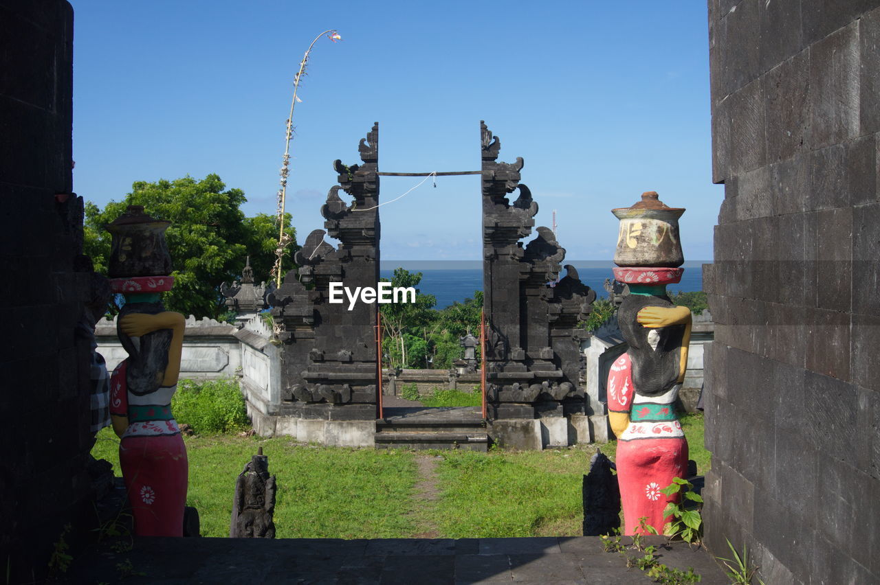 STATUE BY TEMPLE AGAINST BUILDING