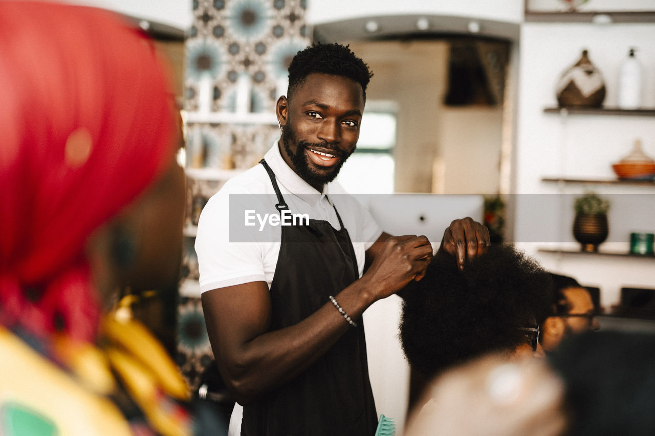 Smiling male hairdresser talking with female coworker in barber shop