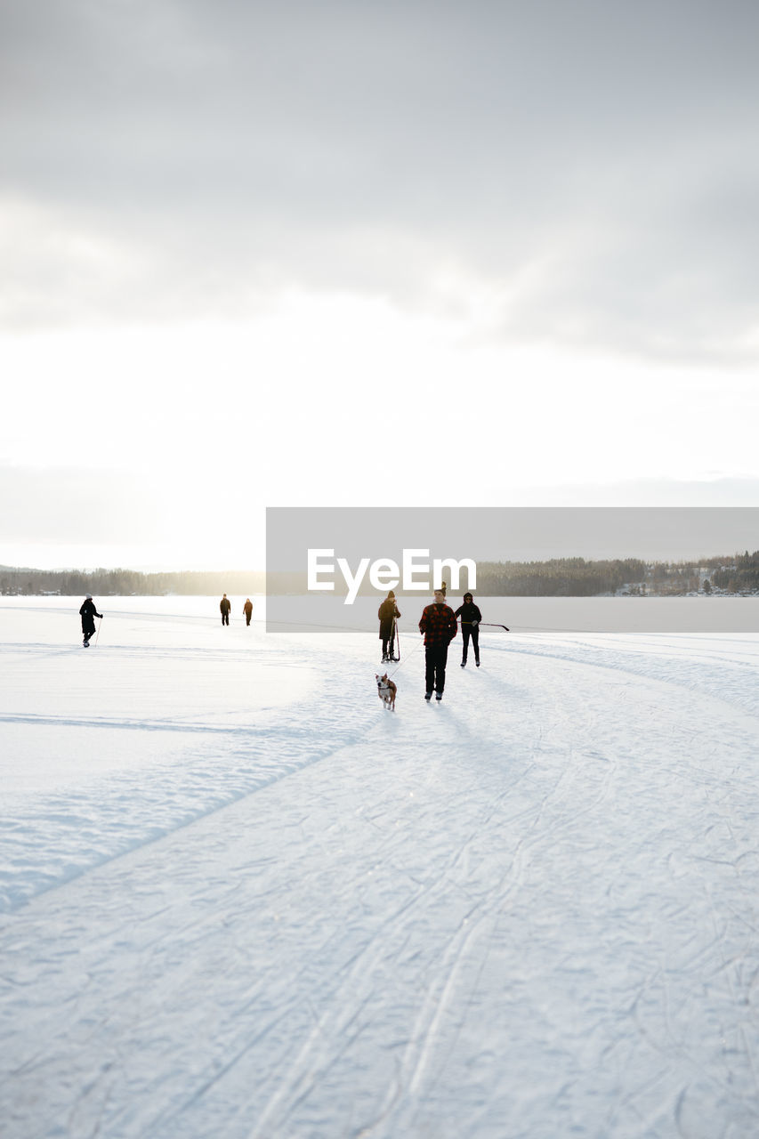 People on snow covered land against sky