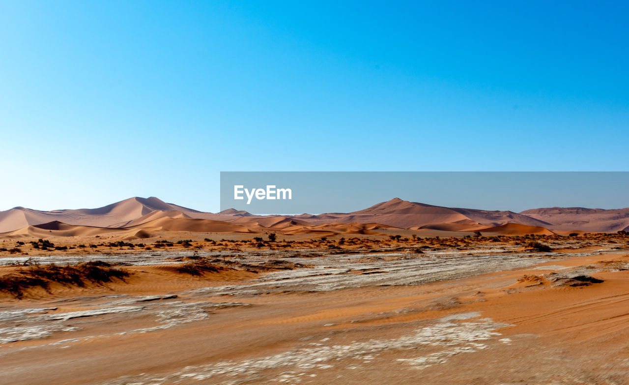 Scenic view of desert against clear blue sky