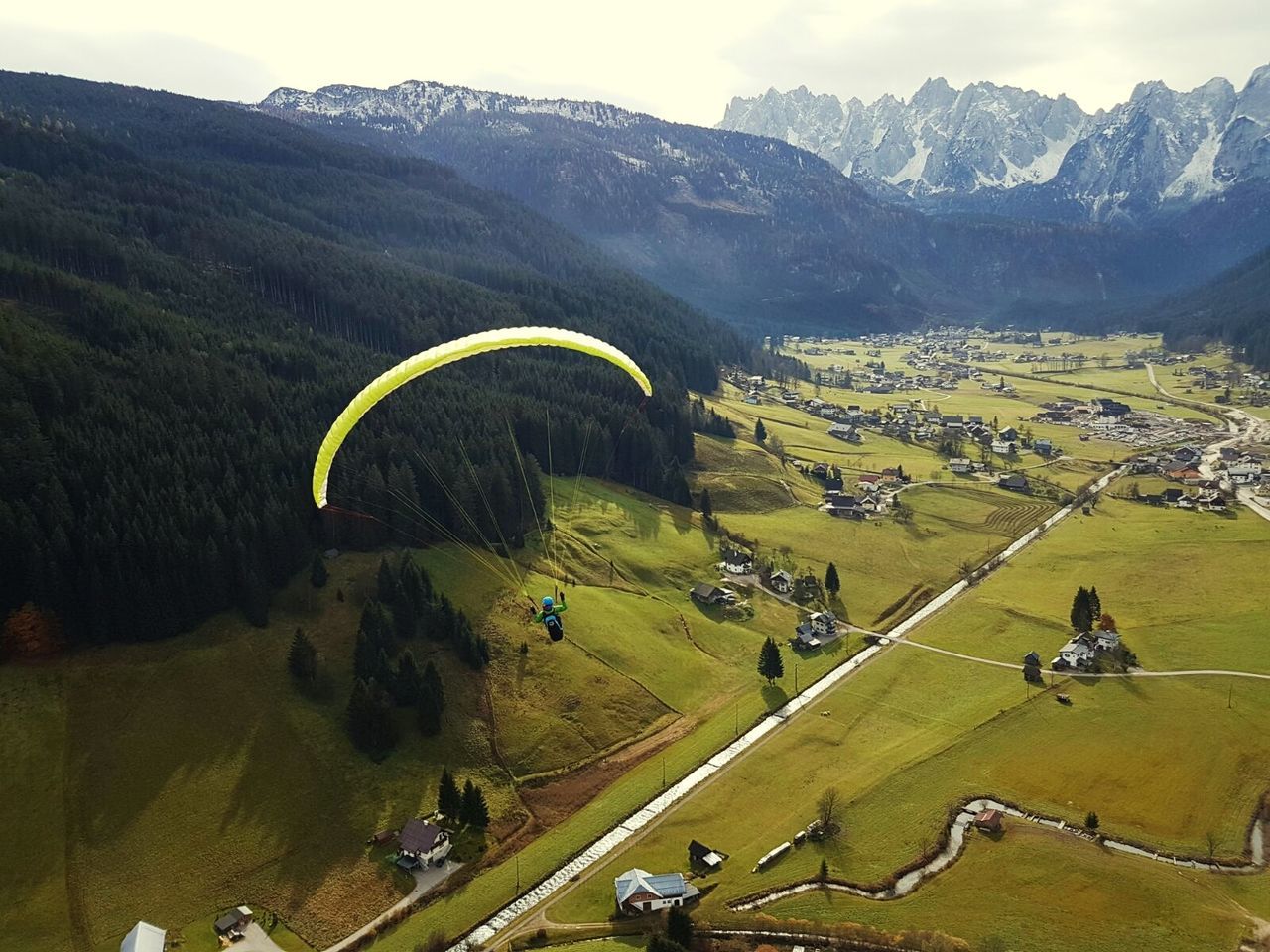 High angle view of person paragliding over landscape