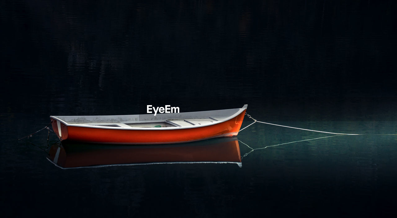 Close-up of boat moored on lake at night